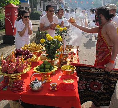 Ma song giving blessings at a road-side altar - note firecrackers