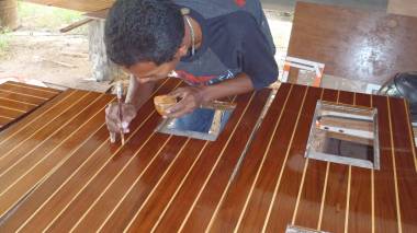 Baw touching up the floorboards with lightly colored varnish