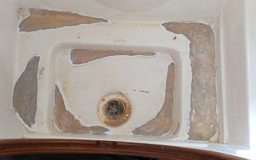 A shower drain with bad gelcoat ground back