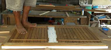 Houa gluing down pre-cut teak strips on a cockpit hatch