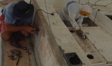 Jon drilling into wet wood while Boy cuts off a sheet of fiberglass