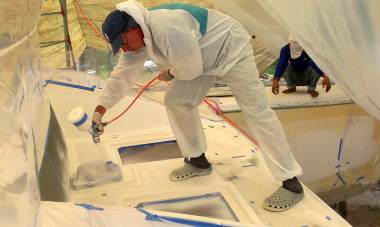 Mike spraying the foredeck inside a plastic tent of masking