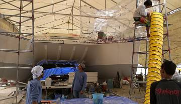 Yando mounting the yellow extractor fan for the spray-tent