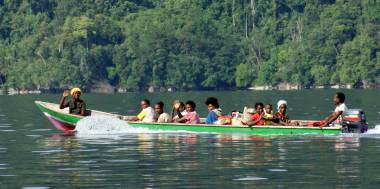 Papuan villagers wave from their long boat