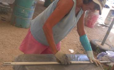 Sue sanding a spreader bar - a latex glove keeps her cast dry
