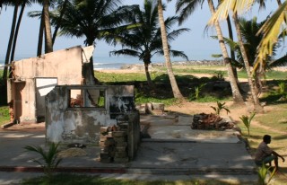 Two years after the tsunami, a man sits on the wreckage of his home.